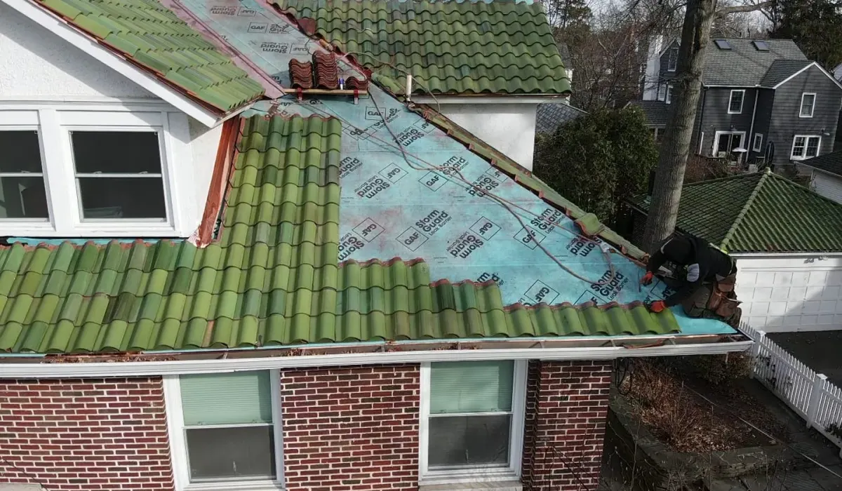 A clay tile roof on a New Jersey home during a tile lift, showing the valley flashing and waterproof underlayment beneath the tiles